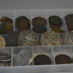 Moneta rara in esposizione su un tavolo, con strumenti di valutazione e note informative.